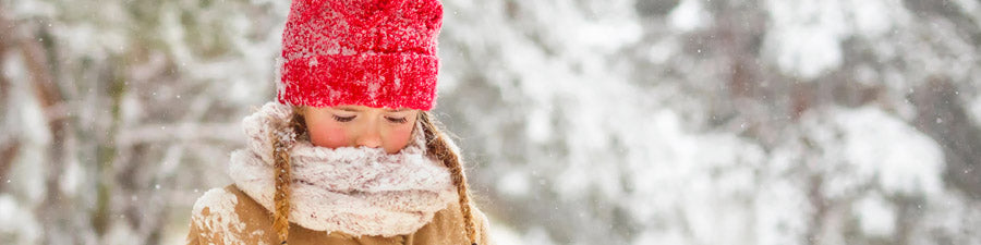 Child outside in winter clothes, including a red winter hat and scarf