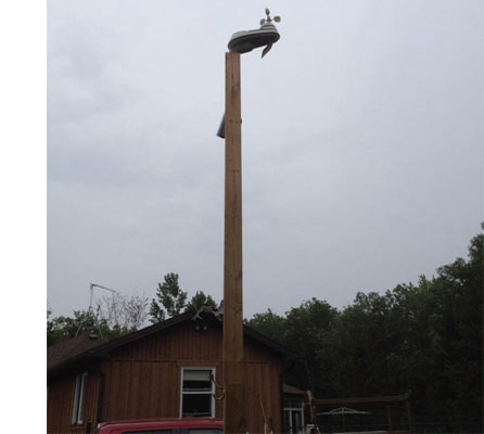 Weather Station mounted on wooden pole high above home in the background