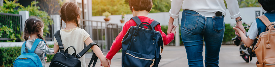 Kids with backpacks and adult walking in a line